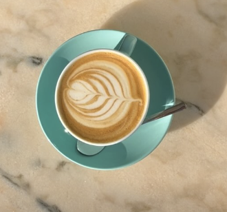 Latte art in a teal cup, shot from above on a saucer